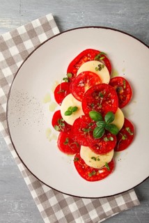 Caprese salad, Italian traditional dish, tomatoes with mozzarella cheese, basil and spices, top