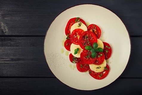 Caprese salad, Italian traditional dish, tomatoes with mozzarella cheese, basil and spices, top