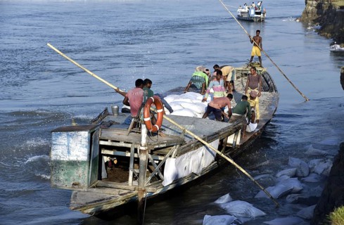 Public Works Department (PWD) of Assam labourer throwing sand bag from boat in the banks of Beki