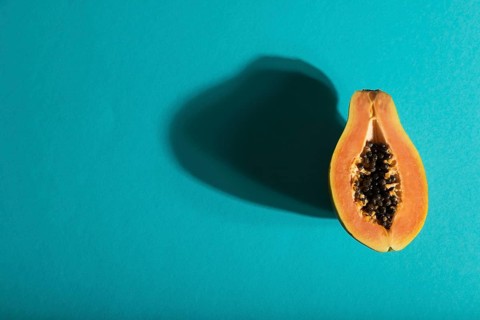 Ripe cut papaya on blue pastel background. Top view, flat lay, copy space, hard light. Tropical,