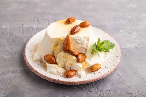 Ricotta cheese with honey and almonds on gray concrete background. side view, close up