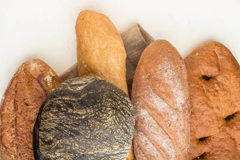 Different kinds of fresh baked bread on a white wooden background. top view, flat lay, close up