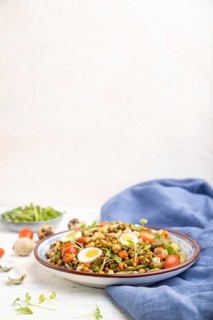 Mung bean porridge with quail eggs, tomatoes and microgreen sprouts on a white concrete background