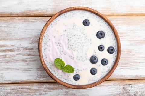 Yogurt with blueberry in wooden bowl on white wooden background. top view, flat lay, close up