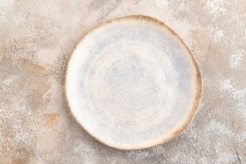Empty blue and white ceramic plate on brown concrete background. Top view, copy space, flat lay