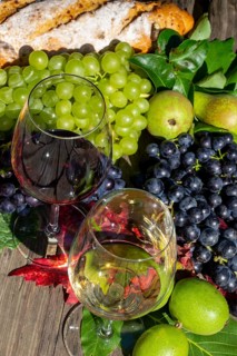 Symbolic image of grape grape harvest: Ripe grapes decorated with wine glasses on a wooden table