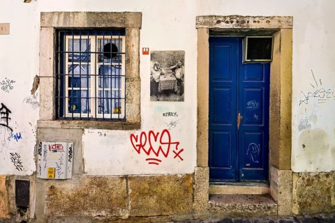 Graffiti and street art on weathered walls of an old building at nighttime, Alfama, Lisbon