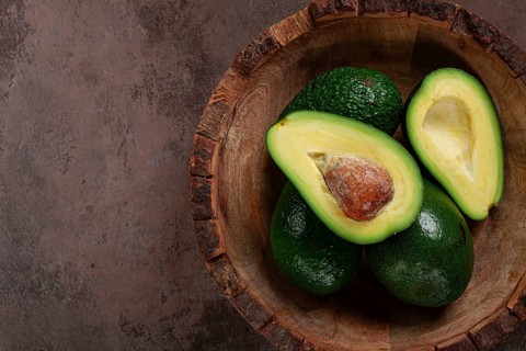 Fresh, sliced avocado, in a wooden plate, top view, food background, concept, food styling