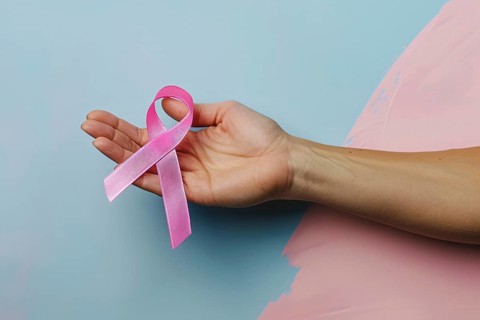 Woman's hand holding pink breast cancer awareness ribbon. Generative AI, AI generated