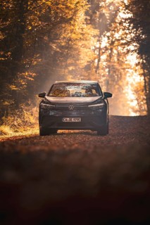 Car on an autumnal forest path, surrounded by golden leaves and bright sunlight, electric car VW