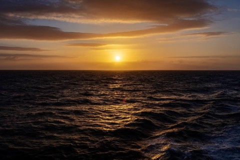 Sunset over a calm sea with clouds and a shimmering orange sky, Celtic Sea