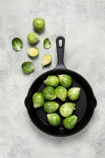 Fresh Brussels sprouts, raw, in a cast-iron pan, top view, on a gray table, no people