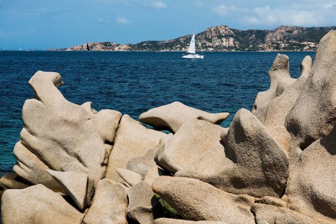 Bizarre granite rocks and sailing ship, Spiaggia del Faraglione, Palau, Costa Smeralda, Sardinia,