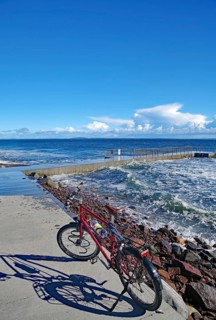 Sun shining on a bicycle on a coastal promenade with a view of the sea and waves, Tönsberg,