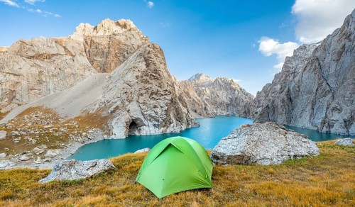 Green tent at the turquoise mountain lake Kol Suu with rocky steep mountains, Kol Suu Lake, Sary