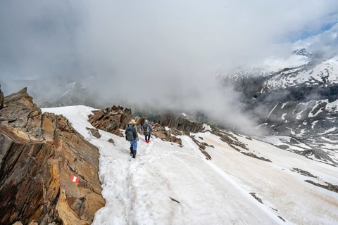 Mountaineer on a rocky ridge with snow, descent from the summit of Schönbichler Horn, view of