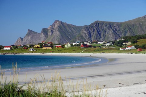 Village off Bergen with colourful houses on a white sandy beach on a sunny day, blue water,