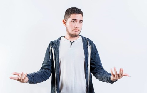 Puzzled person spreading hands isolated. Clueless young man with open arms