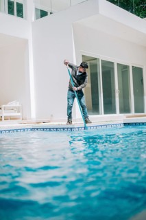 Maintenance person cleaning a beautiful home swimming pool. Worker cleaning a beautiful homemade