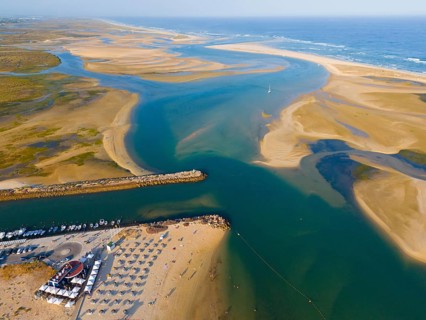 Wide estuary merging into the sea with beaches and boats along the coast, aerial view, Fuseta,