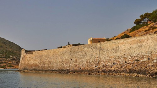 Long, old stone wall along the coastline, surrounded by a hill and calm sea, Venetian Sea Fortress,