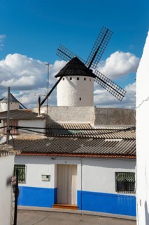White and blue house and windmill under a sunny sky in a rustic village, Campo de Criptana, Ciudad