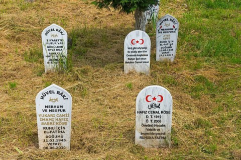 Gravestones with Turkish flags and inscriptions in a meadow with trees in the background, Echinos,