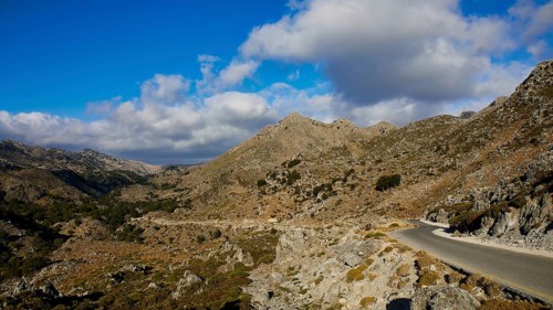 A lonely mountain path runs through a rough, stony landscape under a wide, clear sky, Kallikratis,