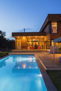 Rear of modern cube style home with stained horizontal wood cladding, in-ground swimming pool and