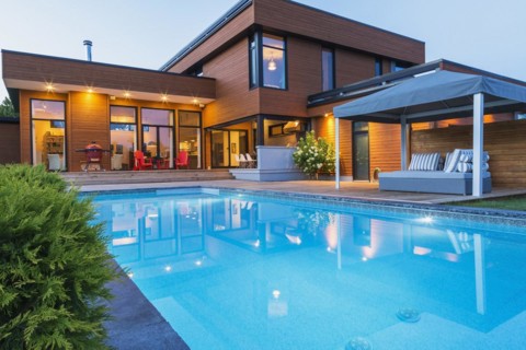 Rear of modern cube style home with stained horizontal wood cladding, in-ground swimming pool and