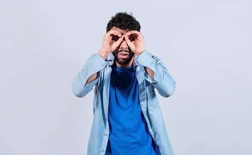 Man making binoculars gesture isolated. Curious man making binoculars gesture isolated