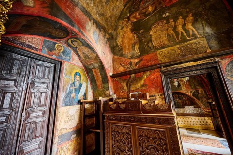 The scene shows an Orthodox icon and wall painting in a room with wooden doors and detailed