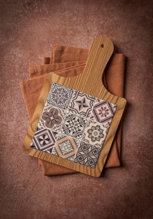 Wooden cutting board with ceramic tiles, on a kitchen towel, top view, food background