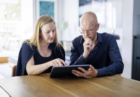 Symbolic photo. A woman and a man sit together at a table with a tablet and talk. Berlin, 13.08
