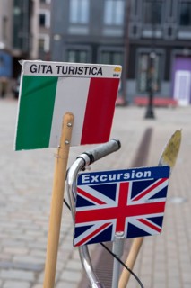 Signs with Italian and English flags show tourists which city tour is taking place in which