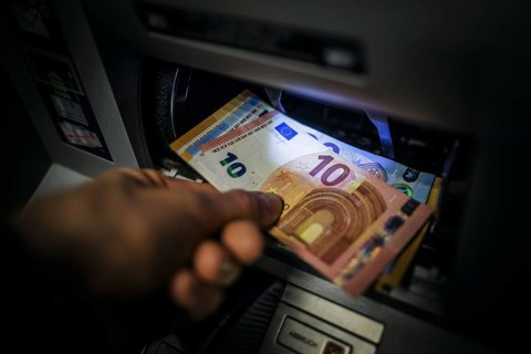 Symbol photo on the subject of withdrawing money from an ATM. Banknotes being withdrawn from an ATM