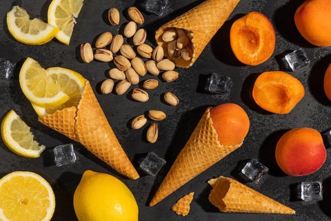 Ice cream cones with lemons, apricots and pistachios with ice cube cubes on a black background