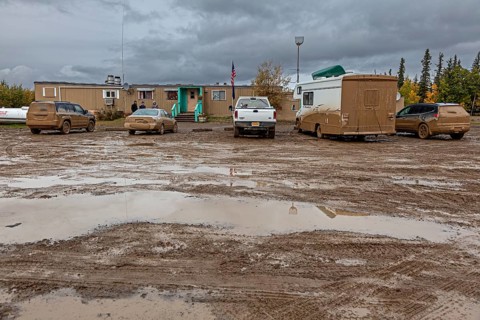 Dirty cars and muddy car park in front of pub, adventure tourism, Dalton Highway, Alaska, USA,