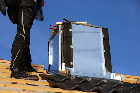 Roofer works on the chimney cladding