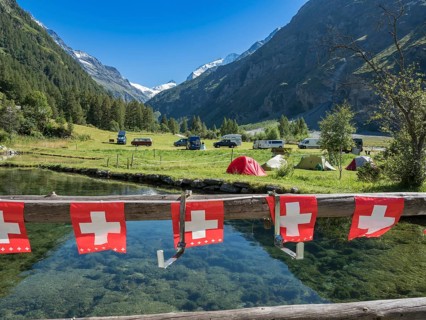 Tents and camper vans on a small campsite, village Zinal, mountain range in the back, Val