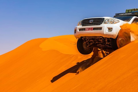 A Toyota Landcruiser crosses a sand dune in the Rub al Khali desert, Dhofar province, Arabian