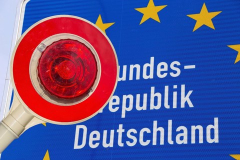 Symbolic image of the asylum debate: trowel in front of a border sign of the Federal Republic of