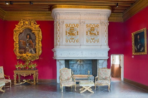 Elegant room with fireplace and framed paintings on red walls, Salon Louis XIV.Chenonceau Castle,