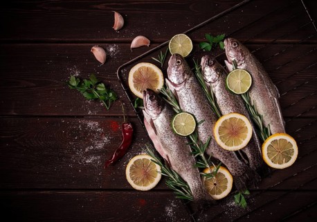 Raw rainbow trout, with lemon and herbs, on a wooden table, no people