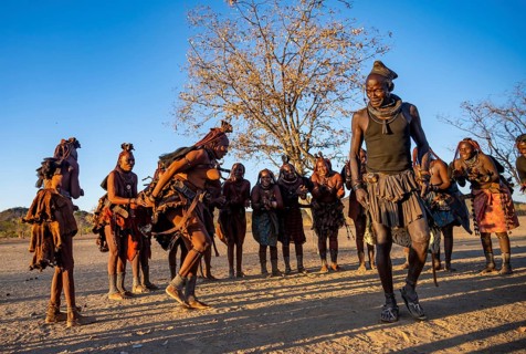 Group of traditional Himba woman with chief of the village standing in a semicircle, clapping and