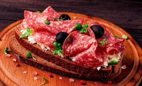 Sandwich, grain bread, with cream cheese and salami, black olives, micro-greens, top view,