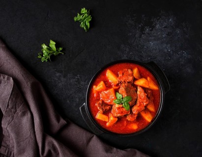 Stew with potatoes, in tomato sauce, with spices and herbs, close-up, no people, on a black