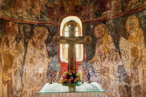 HDR, View of an altar with a cross, flowers and religious wall paintings in the background,