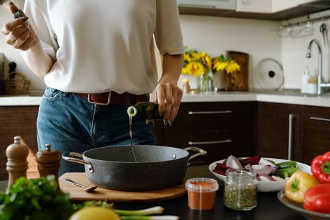 Unrecognizable woman pouring olive oil in an oven pan from bottle