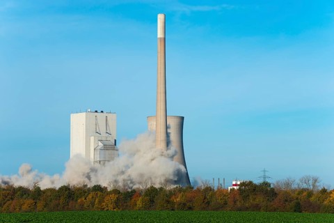 Large cloud of dust envelops an industrial plant in autumnal surroundings under a blue sky,